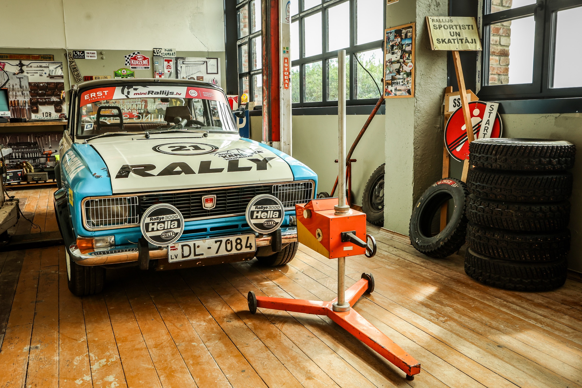 Zili balta rallija automašīna ar numuru 21 garāžas darbnīcā